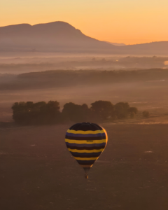 Commercial hot air balloon pilot flying over the Magalies River Valley at sunrise
