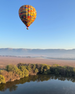 Hot air balloon flying above the Magalies River Valley on a clear winter morning
