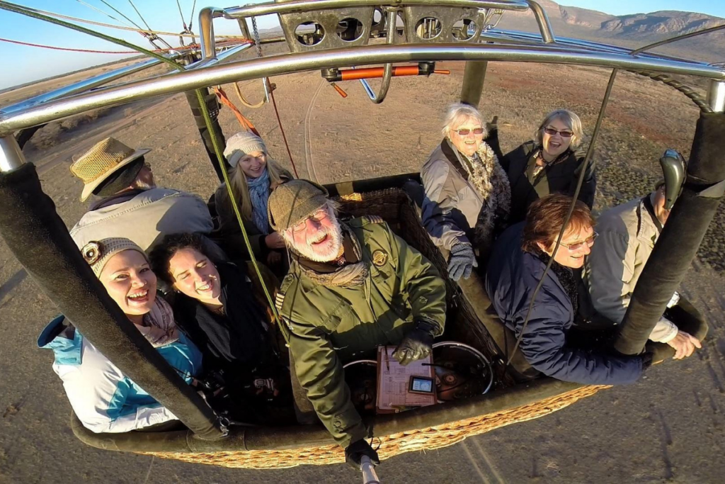 Bill Harrop smiling with passengers in a hot air balloon over the Magalies River Valley
