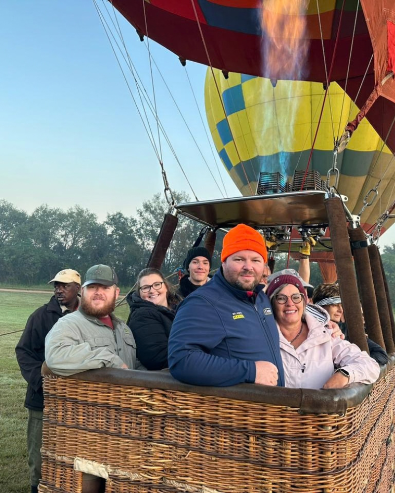 Passengers in a wicker hot air balloon basket as the burner fires before take-off