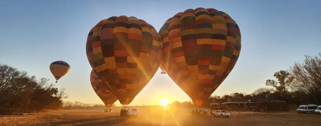Three hot air balloons at sunrise over Bill Harrop's launch field in the Magalies River Valley, South Africa.